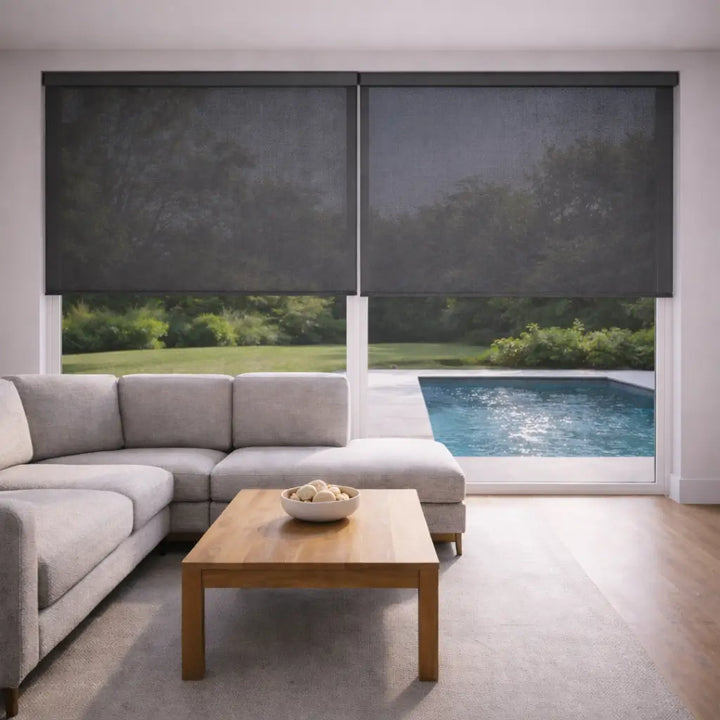 Two Charcoal Sunscreen Roller Shades fully closed in a modern living room, eliminating pool water reflections and cooling the space with diffused light.